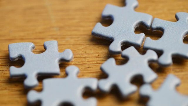 A person try to finish a jigsaw puzzle with small blue pieces, macro footage