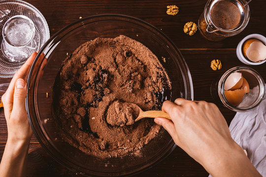 Woman's hands mixing melted chocolate and cocoa powder