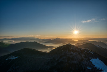 the rise of the sun over the mountains covered by snow with inversion in the valley, slovakia