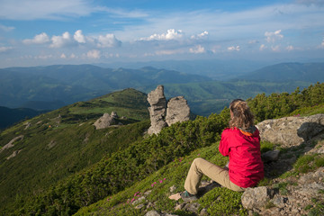 Girl in bright clothes contemplates mountains