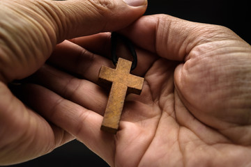 The crucifix is in the hands of a man who is praying for the blessing of his god with faith.