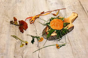 Natural vegan burger on the wooden background, burger with fresh grass. irony about the vegan theme