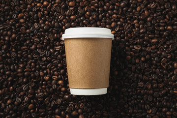 Blank coffee cup on coffee beans background, space for text