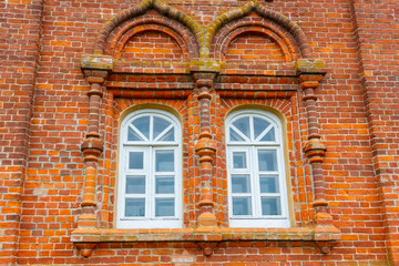 Fototapeta na wymiar Two rounded windows on old red brick wall