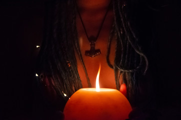 girl with blue dreadlocks conjures at night in a dark room, candle fire and a cow skull - Powered by Adobe