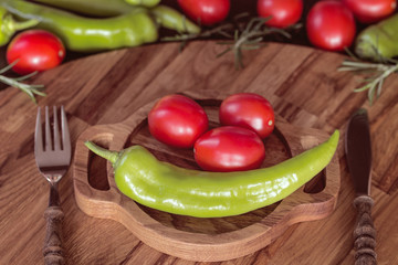 fresh green peppers and tomatoes in a wooden plate close-up. healthy eating concept: fresh vegetables on a served table.