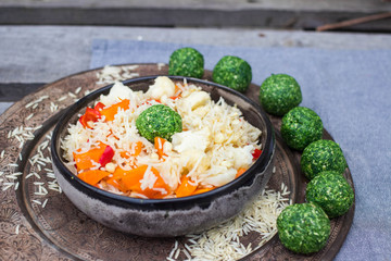 Colorful long basmati rice with vegetables in bowl with spinach green ball. Vegan or vegetarian healthy food.