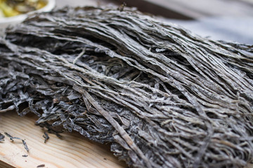 Dry laminaria kelp seaweed on wooden board. Asian traditional sea food used for salads. Vegan or vegetarian food