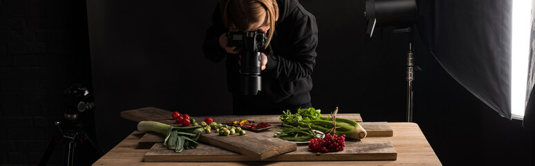 female photographer making food composition for commercial photography and taking photo on digital camera, panoramic shot