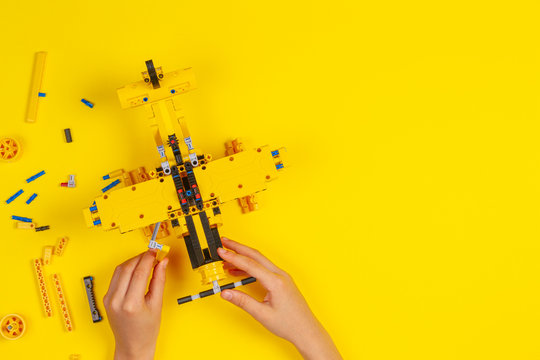 Child hands making construction plane over yellow background. Robotic, learning, technology, stem education for children background