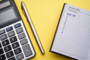 A new year 2020 Wish list concept, with calculator, gold pen, planner and compass. Handwritten headline as Wish List and numbers listed 