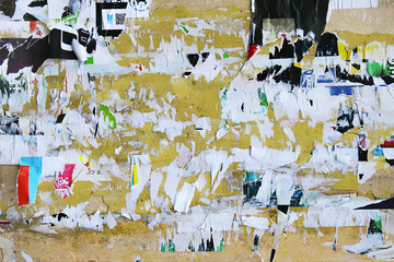 Dirty street yellow wall with old torn and peeling poster paper