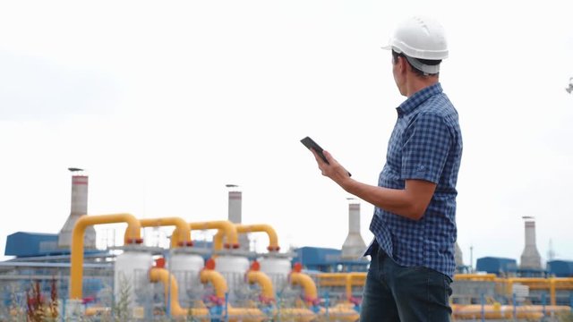 A male engineer in a helmet and a tablet checks the operation of a gas production station. Gas Testing