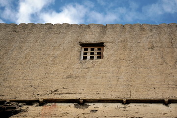 Small traditional window with a wooden mesh on a beige wall in a residential building of the city of Samar in Nepal, Mustang district.