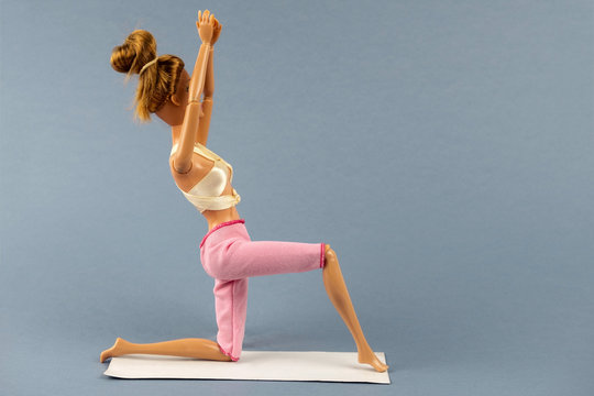 plastic doll in yoga pose on a gray background , healthy lifestyle concept