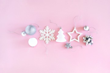 Christmas composition of white and silver decorations on a pastel pink background. Minimalistic holiday concept. Top view, flat lay.