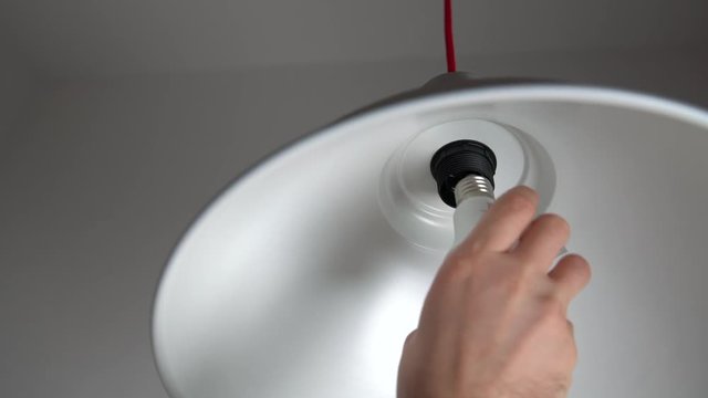 Man uninstalling light bulb from ceiling light