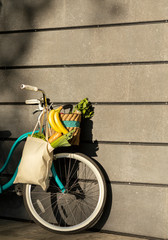 Blue retro bicycle with shopper and healthy products over gray concrete wall