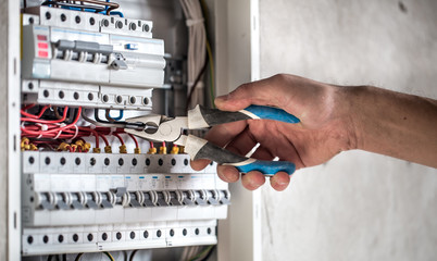 Man, an electrical technician working in a switchboard with fuses. Installation and connection of...