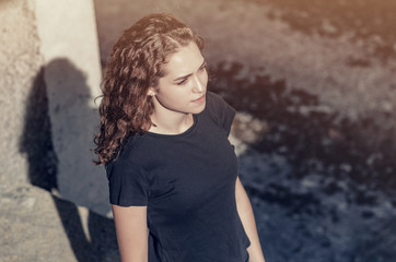 Nice girl with long curly hair. Top view, goes along the industrial zone, concrete building.