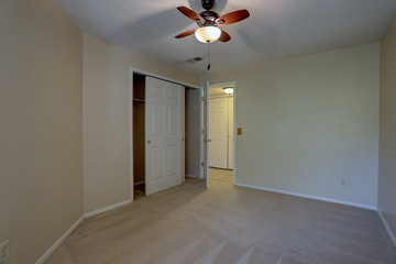 Vacant, carpeted bedroom with ceiling fan in condominium apartment complex