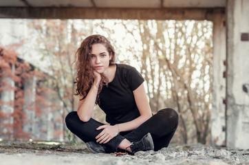 Fototapeta na wymiar Nice girl with long curly hair sits cross-legged