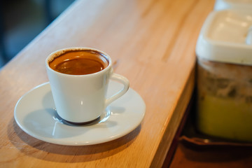 Focus selection: Coffee in a white cup placed on a counter table in a warm atmosphere
