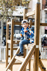 Cute little kid playing on a wooden playground