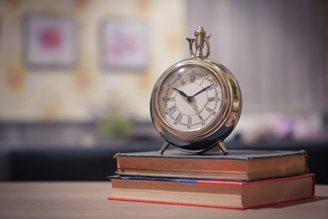 Focus selection:The clock is on two books on a wooden table