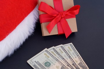 Santa Claus hat, Christmas gift box and USA dollar banknotes. Money for Christmas gifts concept. 