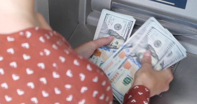 Woman counting money near cash machine outdoors, closeup