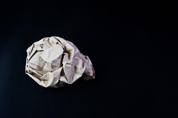 Crumpled clump of paper on a dark background close-up. Crumpled sheet of paper