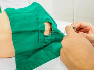Closeup detail of a physician measuring the lumbar pressure of a pediatric practice dummy using a manometer, used to diagnose meningitis. Healthcare and medical education. - 306958388