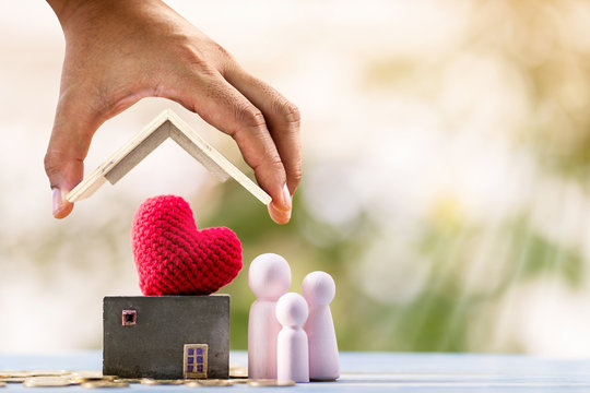 Investor hand hold to open a roof and home model keep a red heart and stack gold coin with growing interest value and wood family in the public park, Loan for business investment real estate concept.
