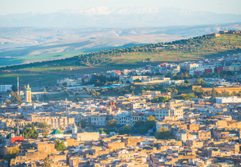 Houses of Fez city in Morocco with mountains on background and sunset light