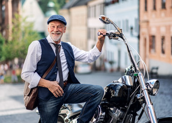 A senior businessman with motorbike in town.