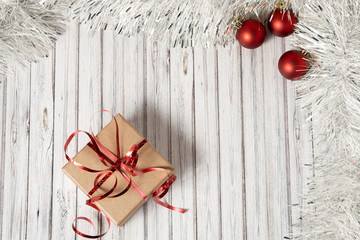 Gift box on a wooden table decorated with a garland and red Christmas balls for the New Year or...
