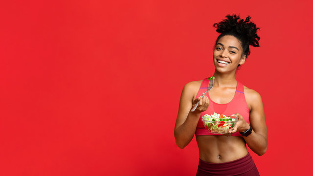 Happy african american fitness woman eating vegetable salad