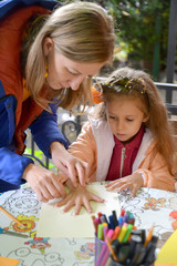 KALININGRAD, RUSSIA. Teacher outlines child 's hand on paper. Outdoor Children 's Master Class