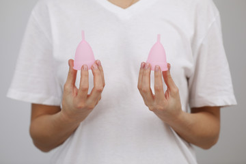 Pink menstrual cups. Close up of woman hand holding different size menstrual cups. Women health...