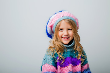 little blonde girl smiling in knitted hat and sweater on white background isolate, space for text