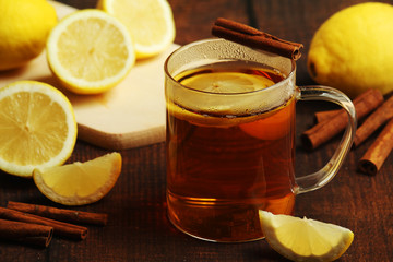 A mug with hot tea with lemons and cinnamon sticks