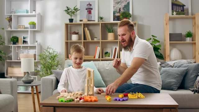 Father and son play with the constructor in the living room