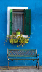 pared azul con ventana maceta verde y banco