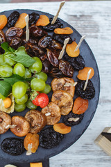 Black plate with different kinds of dried fruits.