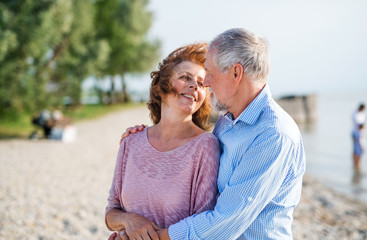 Obraz premium Senior couple on a holiday on a walk by the lake, hugging.