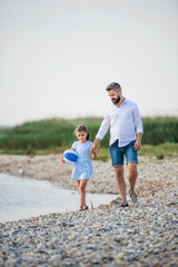 Mature father and small daughter on a holiday walking by the lake.