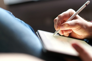 Hand schreibt mit einem Eingabestift auf einem Tablet