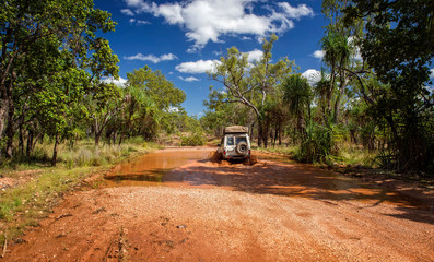 Western Australia – Flooded Outback gravel road with 4WD car crossing the waterhole at the savanna © HLPhoto
