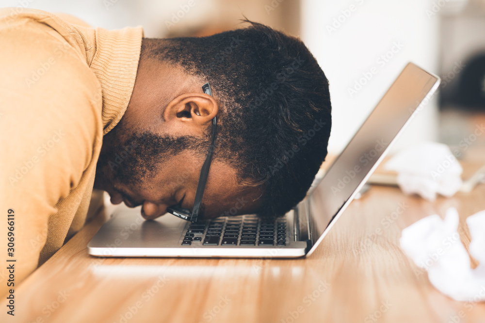 Wall mural overworked businessman with head down on computer